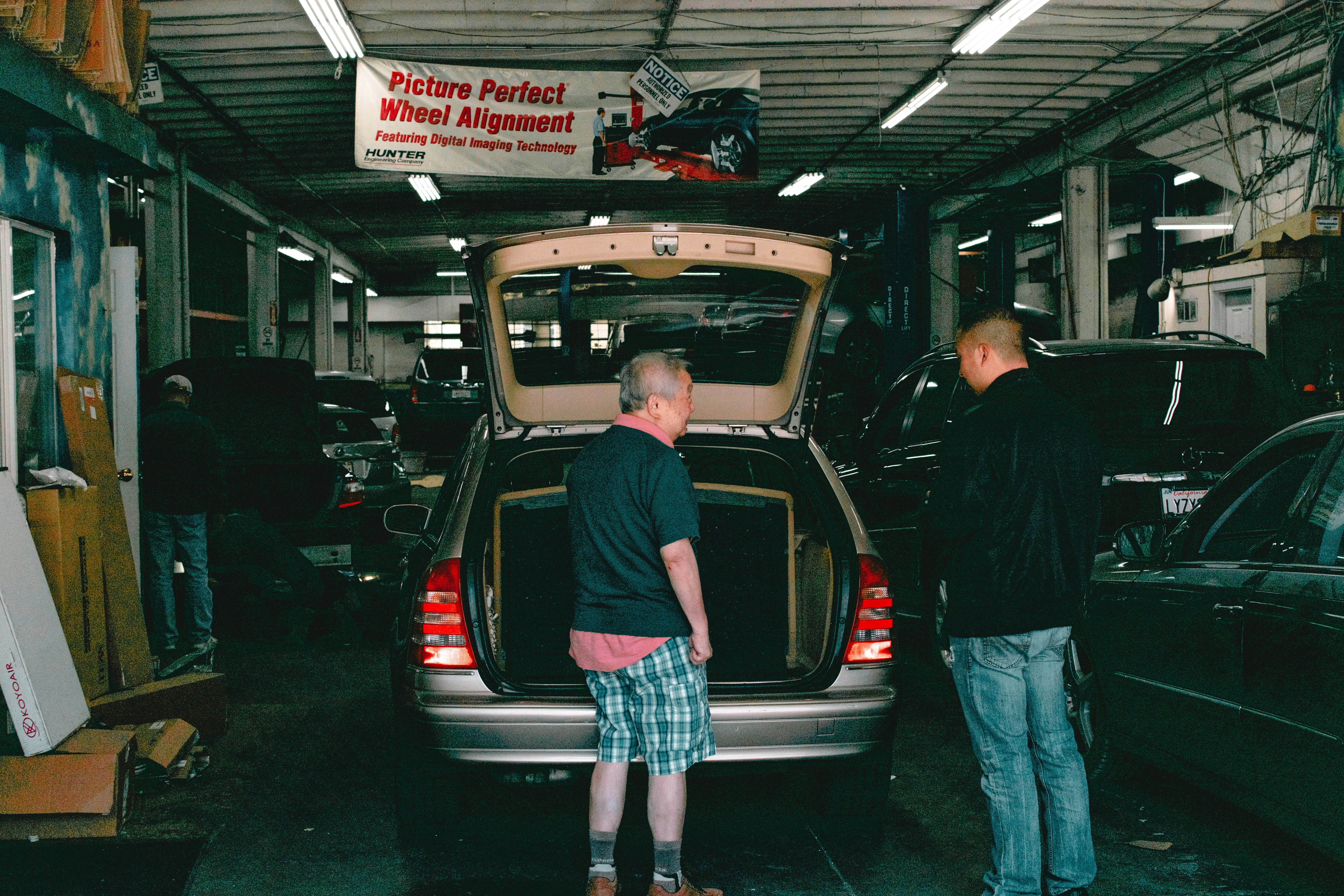 Mechanic inspecting the engine bay and high-voltage components of a used car