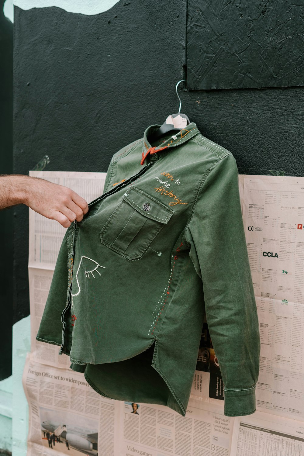 person holding green denim jacket