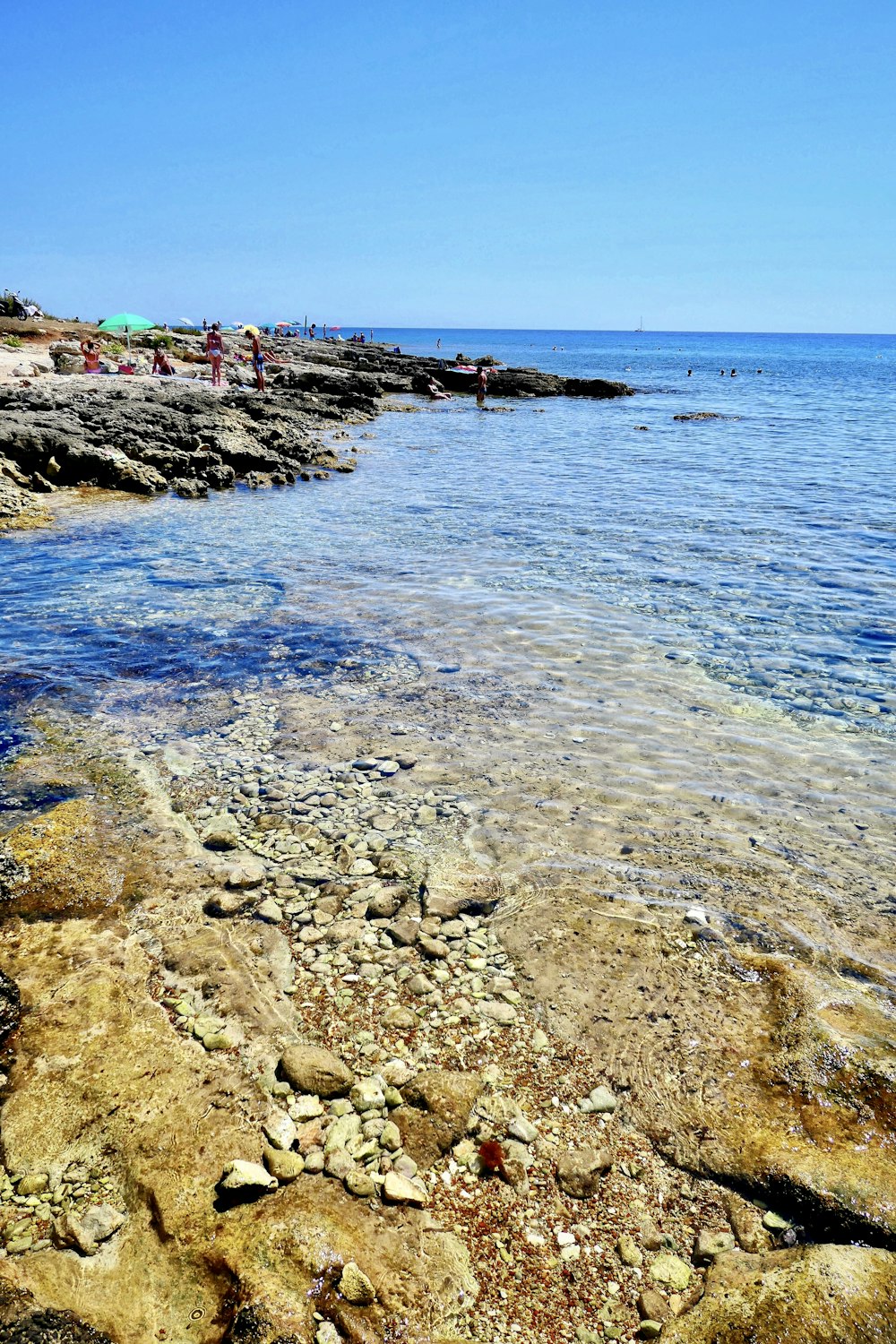 body of water near brown and green mountain under blue sky during daytime