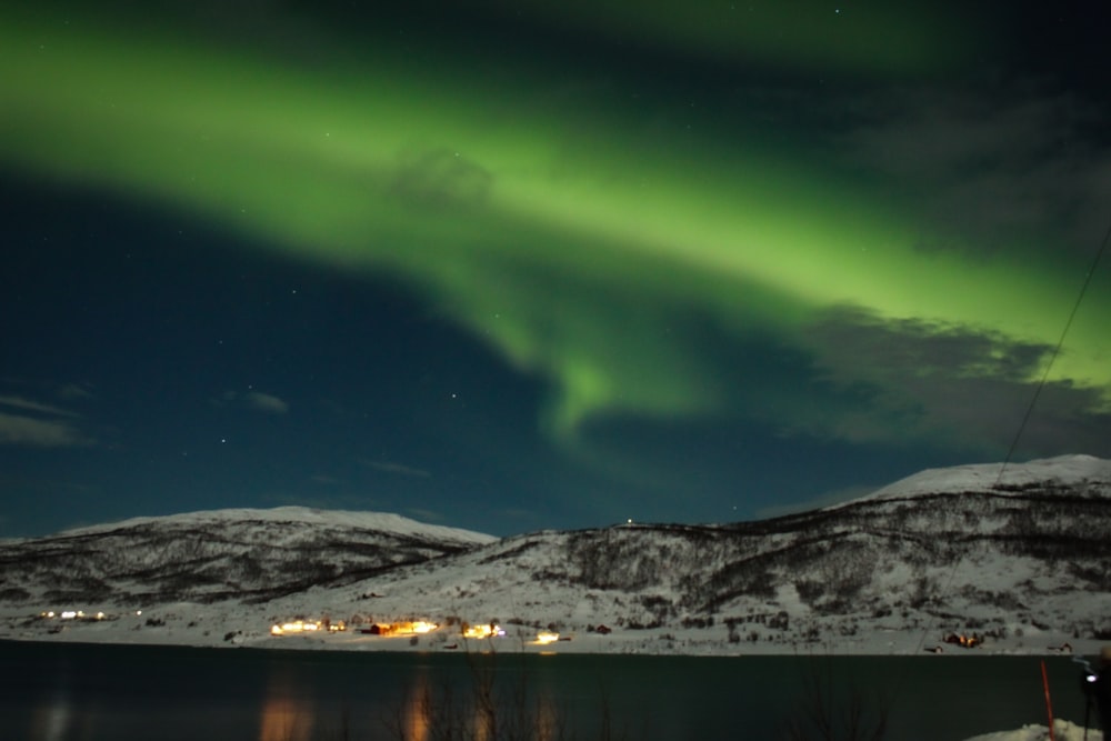 snow covered mountain near body of water during night time