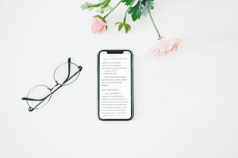 black framed eyeglasses beside pink rose