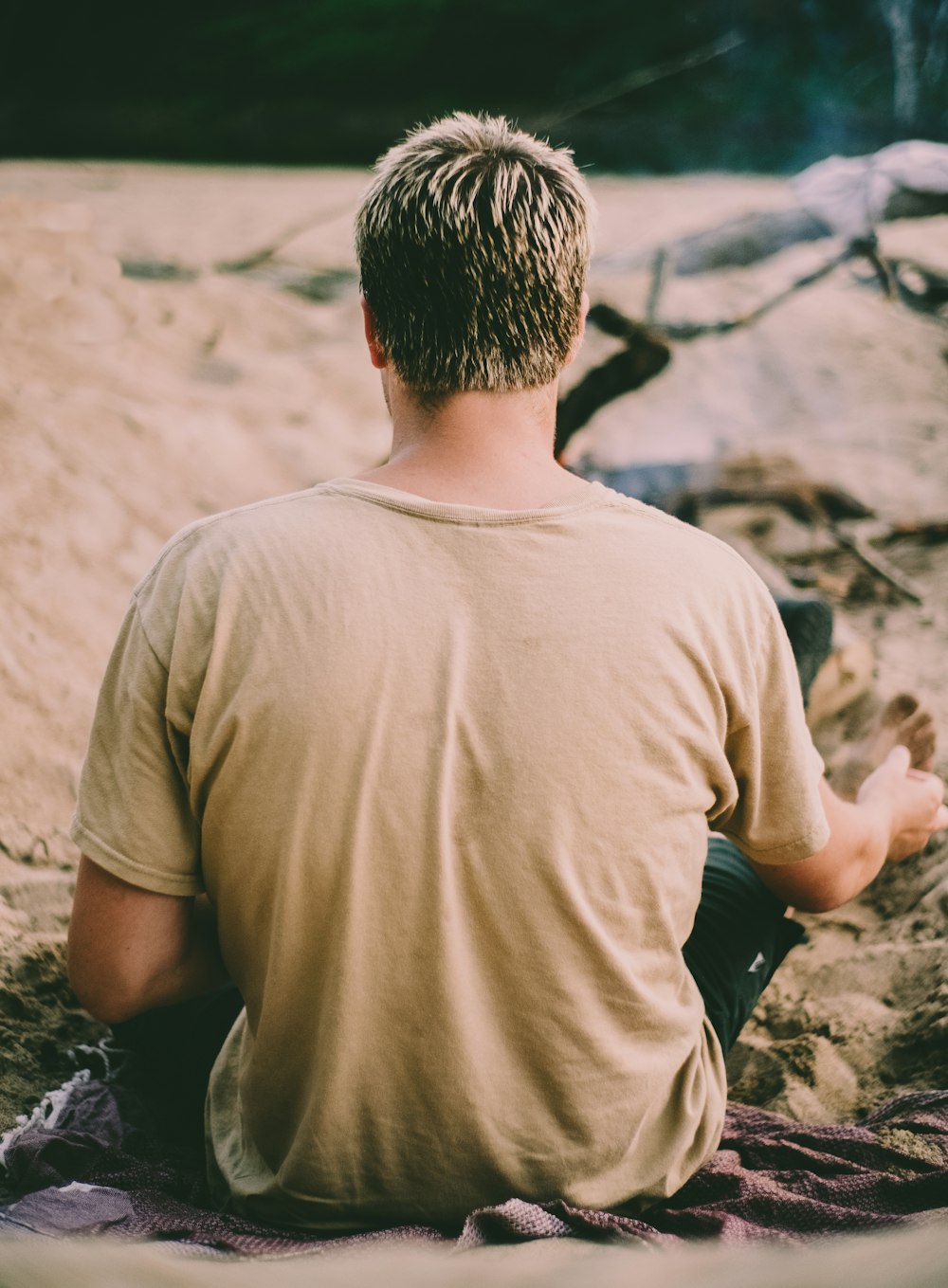 Hombre con camiseta marrón de cuello redondo sentado en la roca durante el día