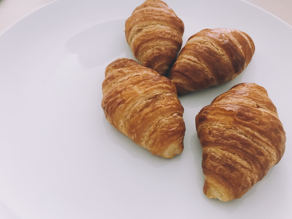 tres panes morenos en un plato de cerámica blanca