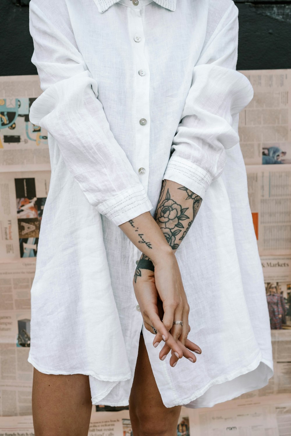 woman in white coat with black floral tattoo on left arm