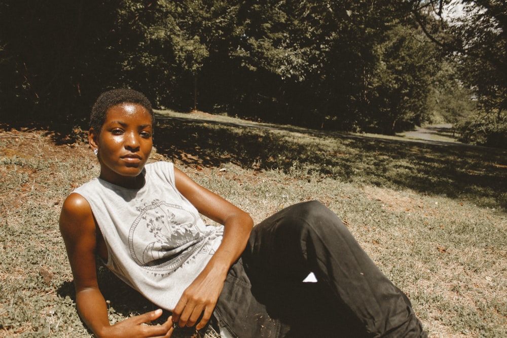 man in white tank top sitting on ground