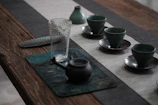 A rustic wooden table set with bright, hand-thrown stoneware cups and a teapot.