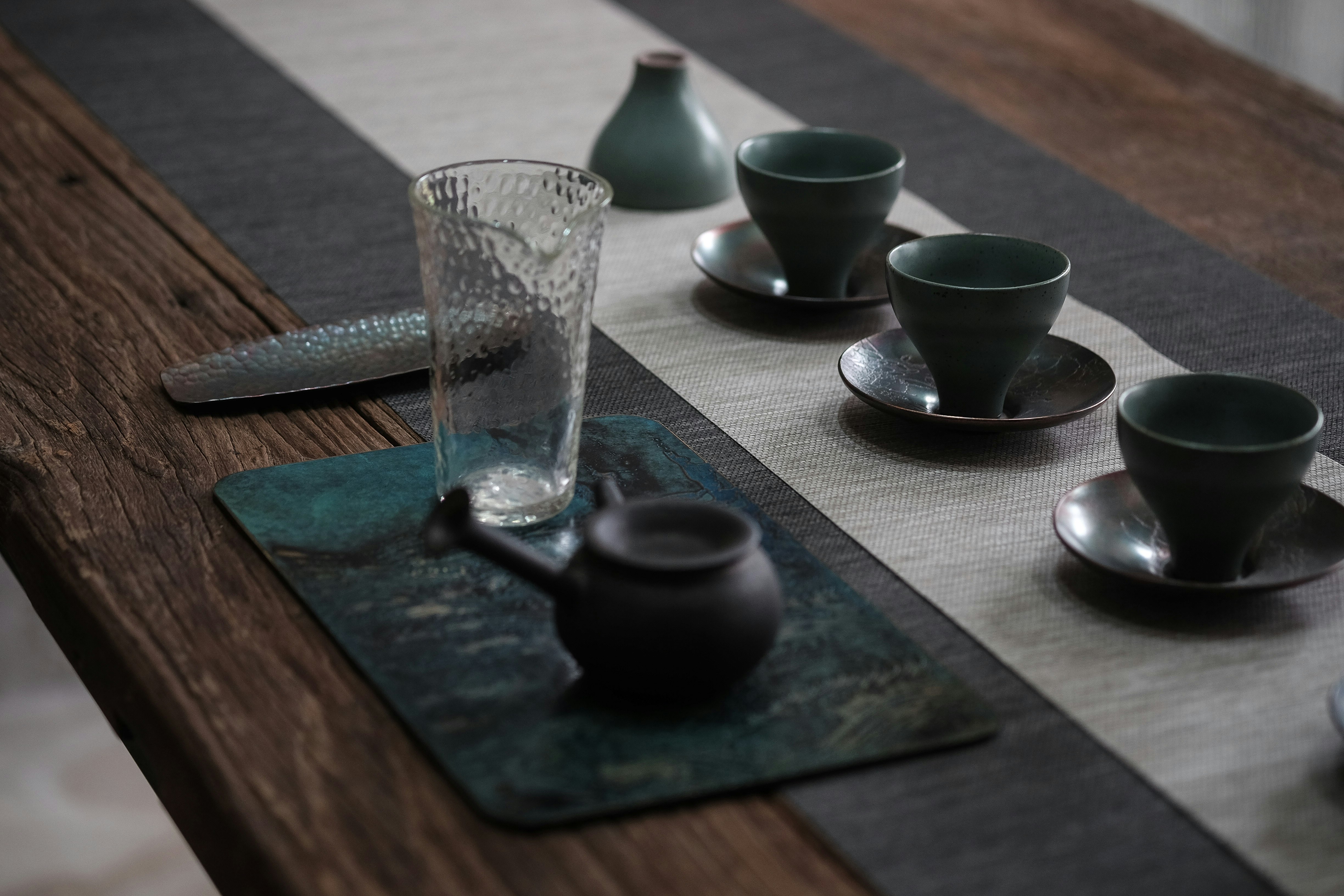 clear drinking glass beside black ceramic bowls on brown wooden table