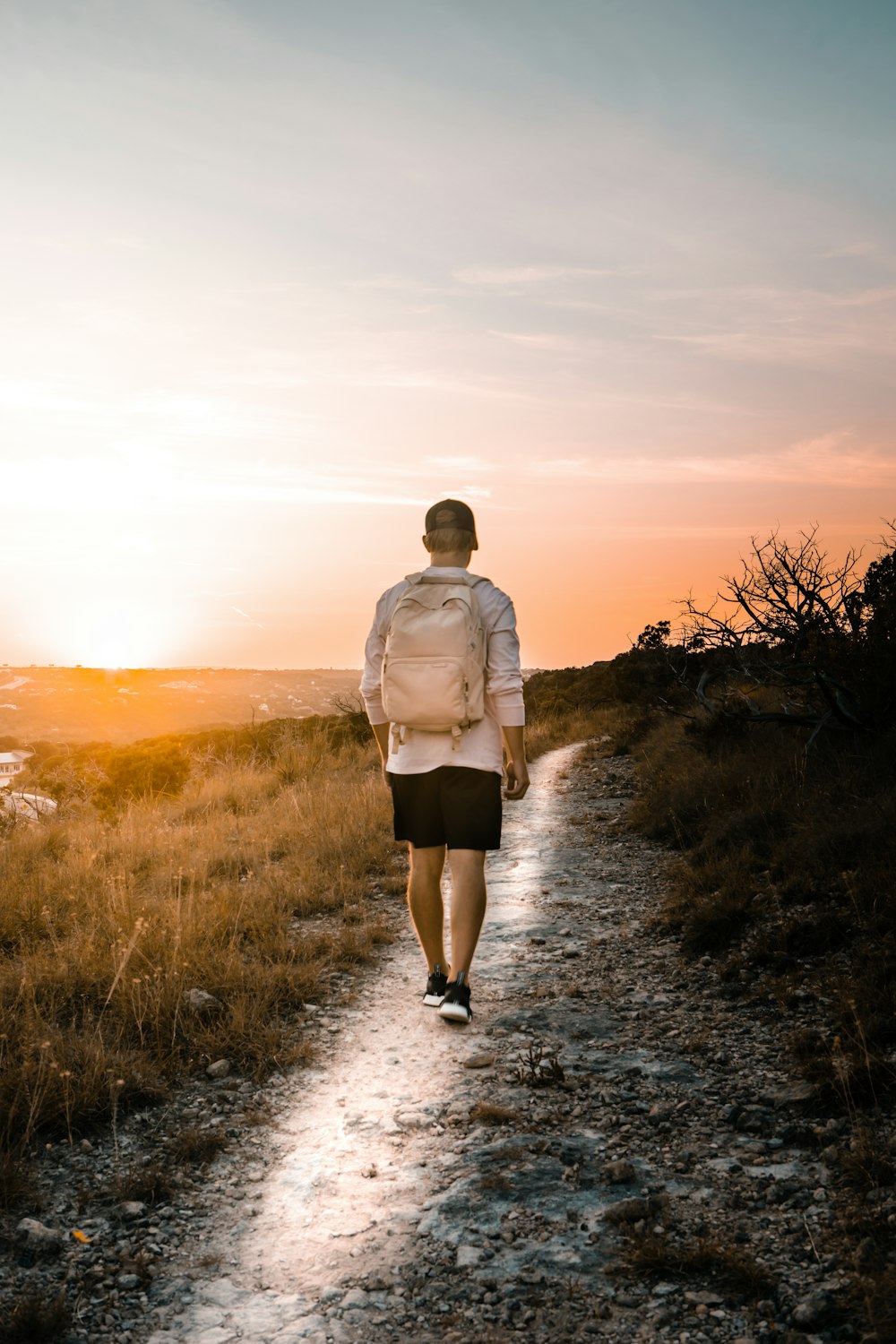 man in white dress shirt and brown shorts walking on dirt road during daytime