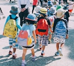 group of people wearing white and orange backpacks walking on gray concrete pavement during daytime