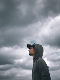 Slate-colored hooded sweatshirt styled with streetwear elements against a backdrop of rainy city streets.