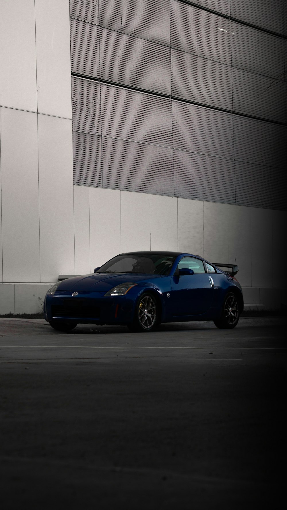 blue porsche 911 parked near white wall