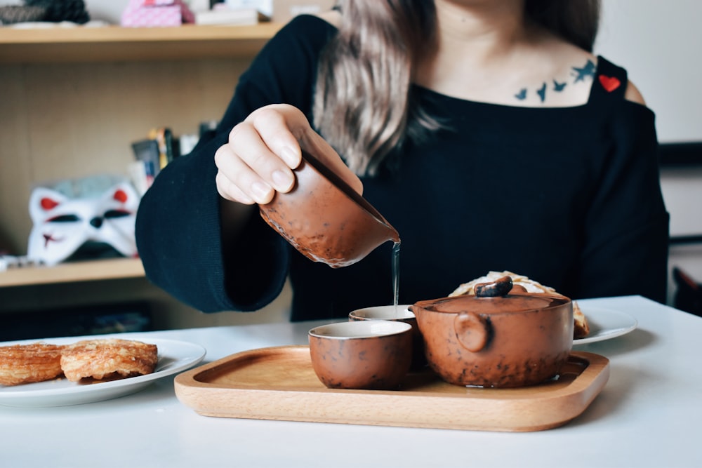 茶色の革のバッグを持つ黒い長袖シャツの女性