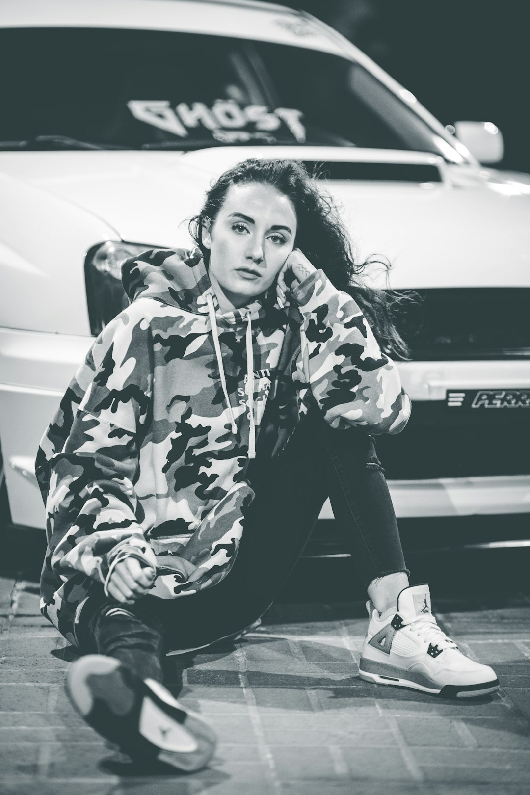 grayscale photo of woman in floral long sleeve shirt and pants sitting on road