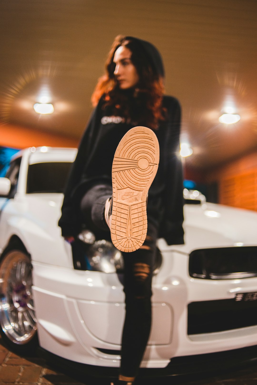 woman in black jacket standing beside white car