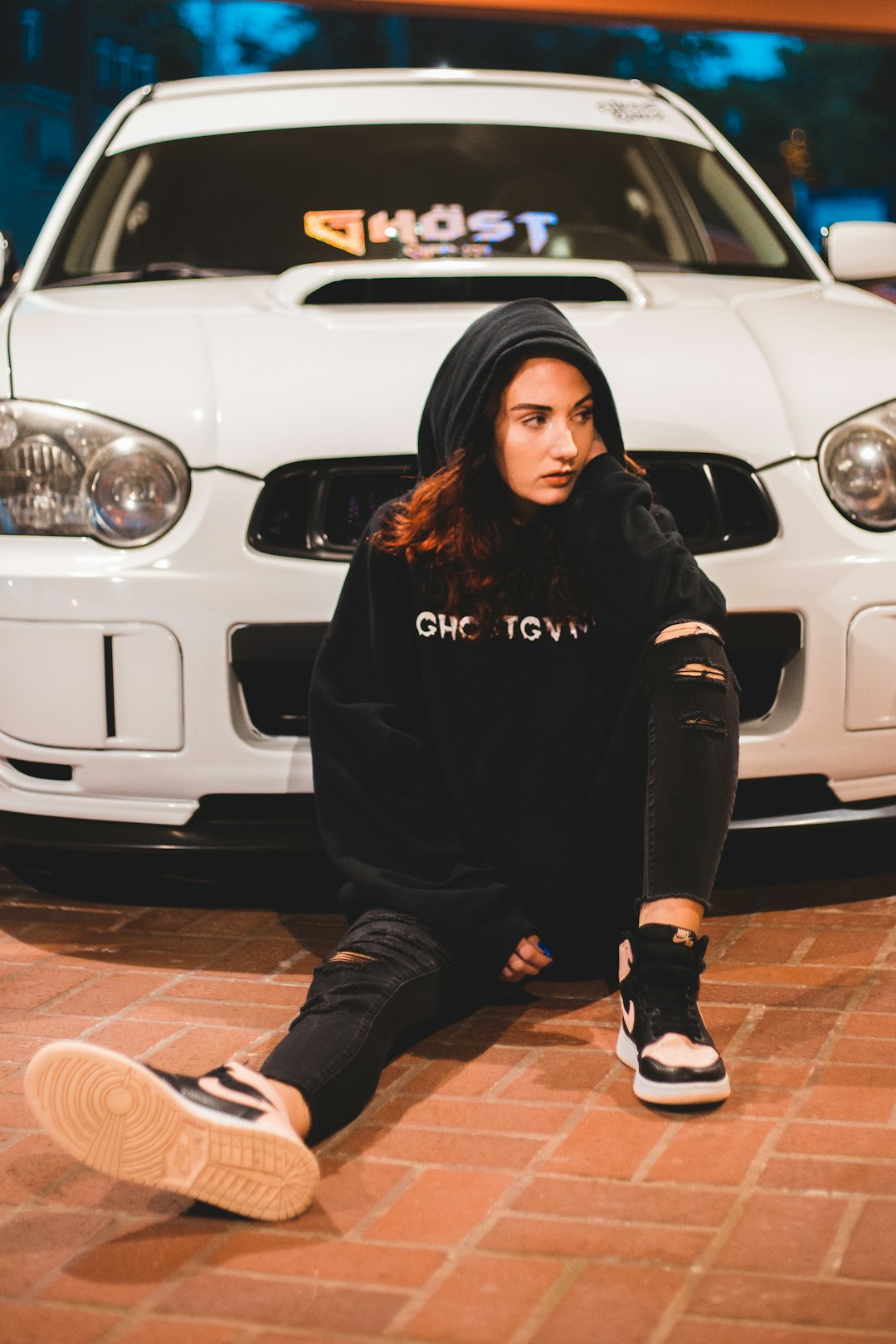 woman in black hoodie and black pants sitting on white car