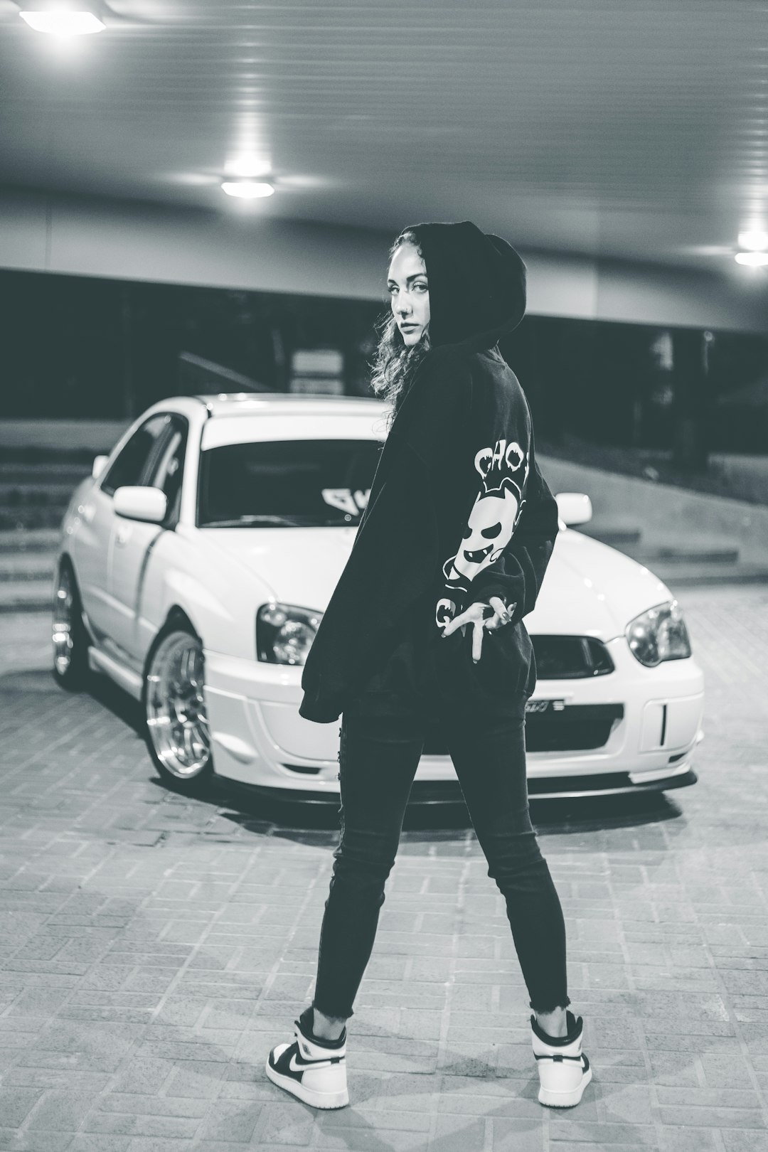 man in black hoodie standing beside white car