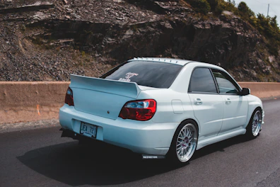 Aerodynamic white spoiler on a modern sedan driving on a coastal highway