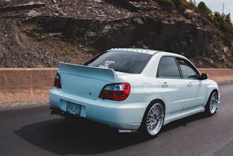 Aerodynamic white spoiler on a modern sedan driving on a coastal highway