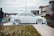 A clean car parked on a residential driveway with a professional washing it outdoors.