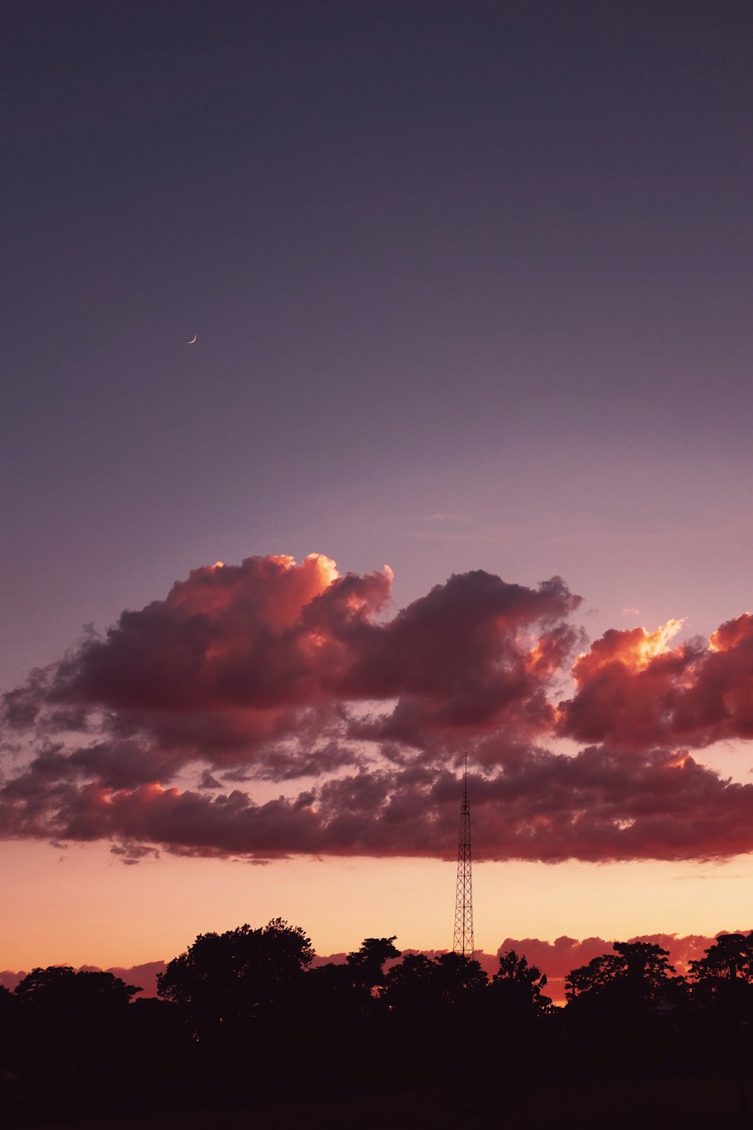 silhouette of tower under cloudy sky during sunset