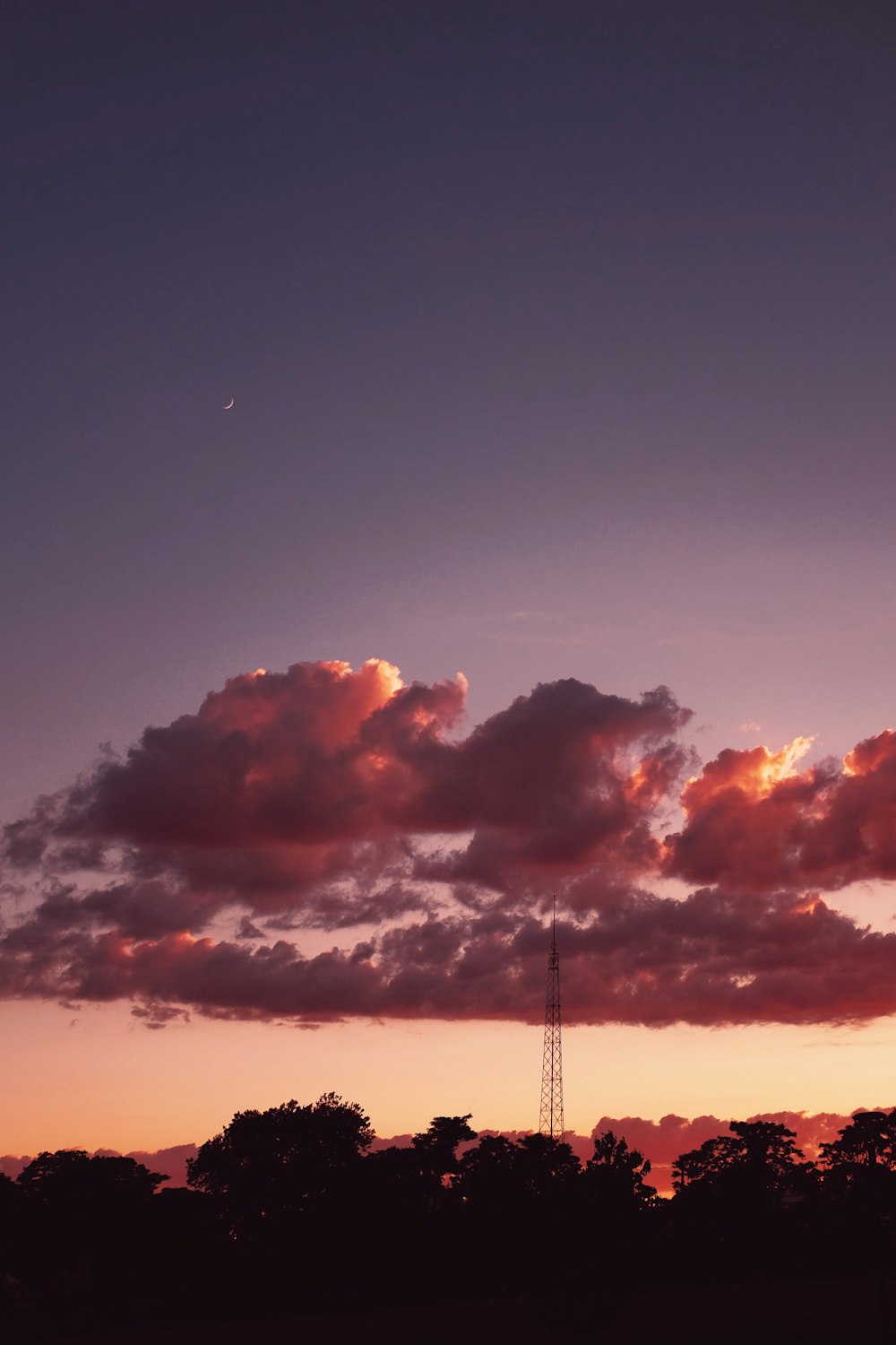 silhouette of tower under cloudy sky during sunset