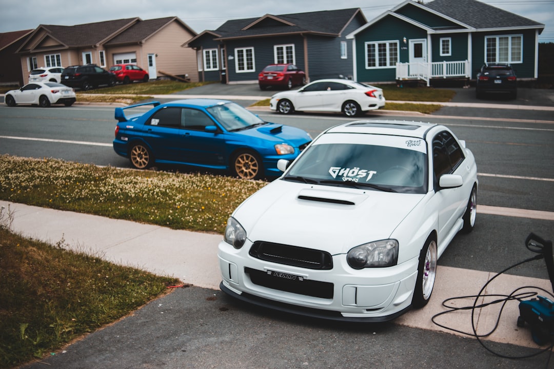 white honda car parked beside blue 5 door hatchback