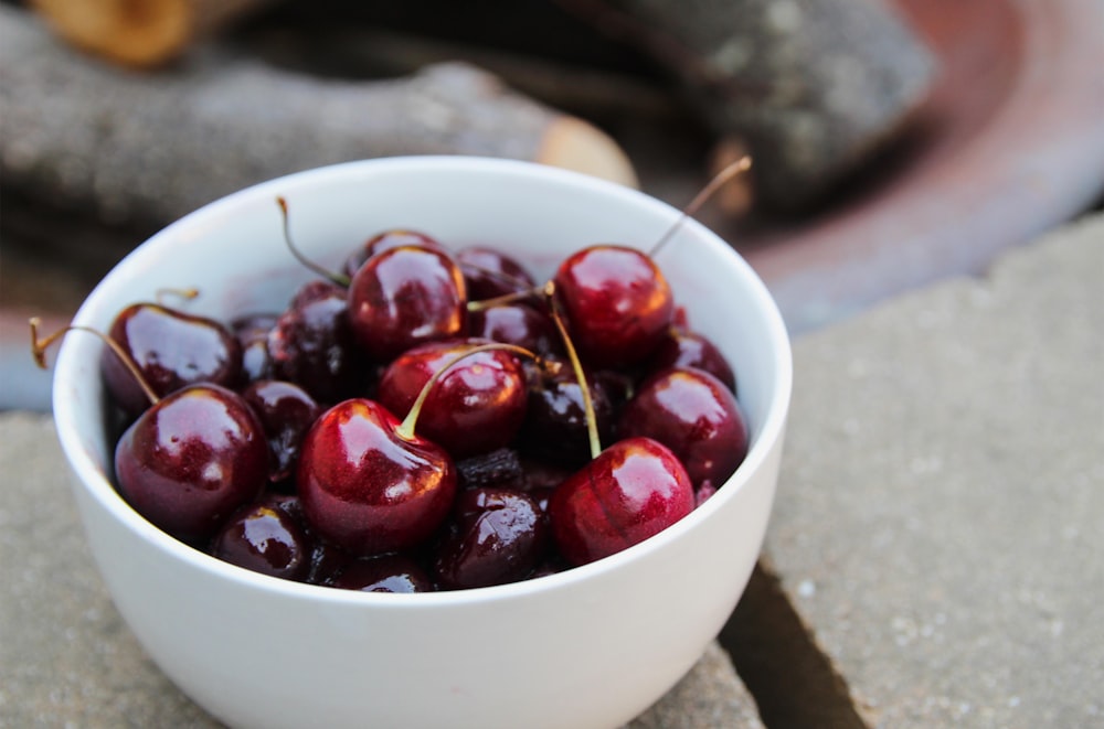 red cherries in white ceramic bowl