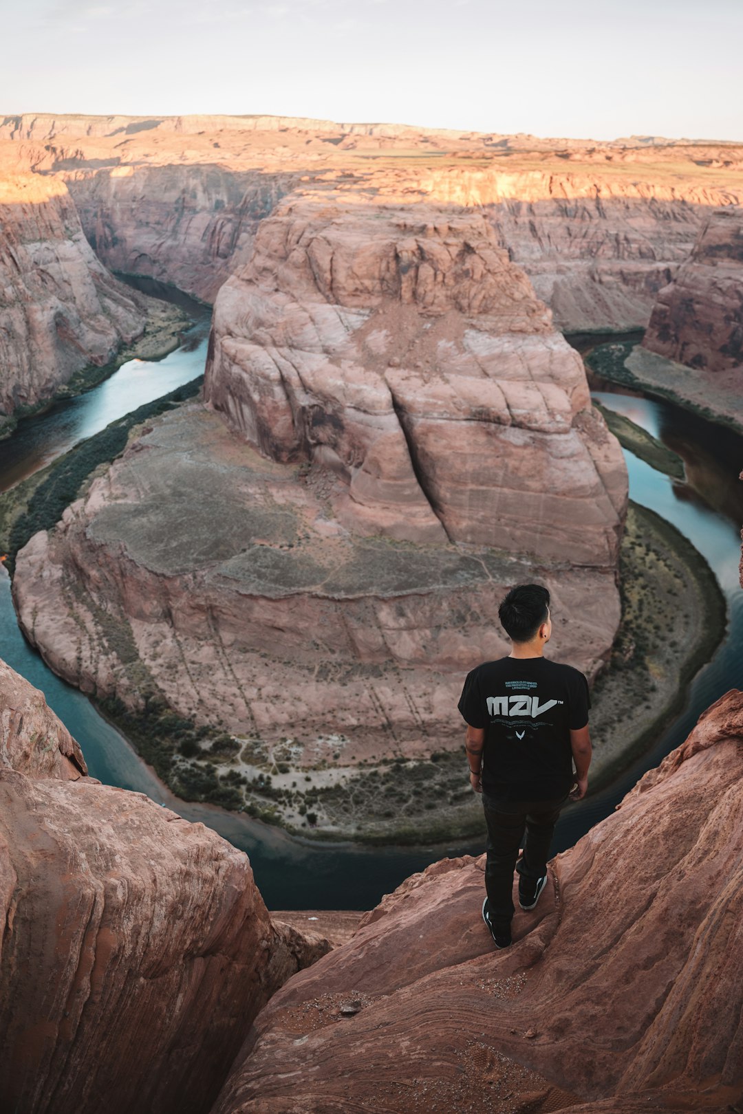 man in black jacket standing on brown rock formation during daytime