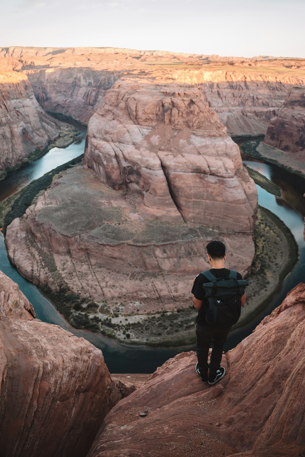 man in black jacket and black pants standing on brown rock formation during daytime