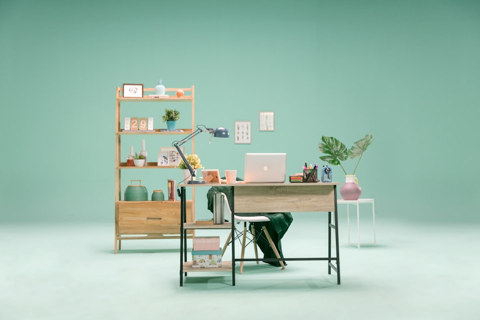 A neatly arranged workspace in a minimalist room with pastel green walls.
