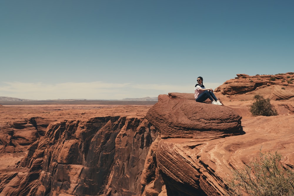 man in black t-shirt sitting on brown rock formation during daytime