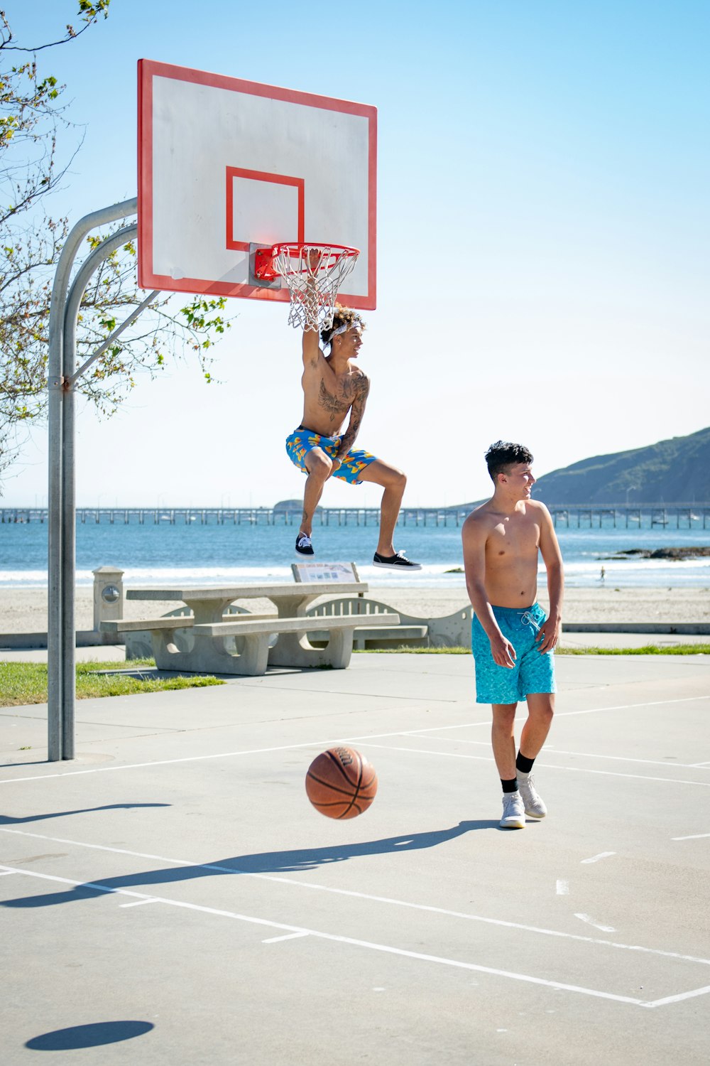 昼間、バスケットボールコートでバスケットボールをする2人の男性