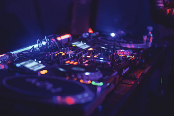 Close-up of a DJ mixer and turntables lit in neon