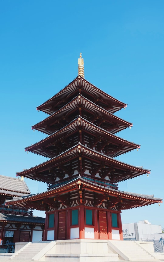 black pagoda temple under blue sky during daytime in Shitennoji Japan