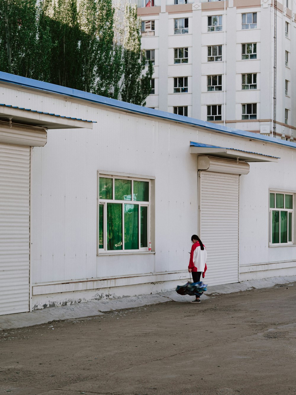 woman in red jacket and black pants sitting on white wooden window during daytime