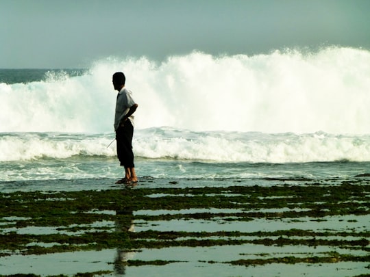 man in black jacket standing on water in Gunung Kidul Indonesia