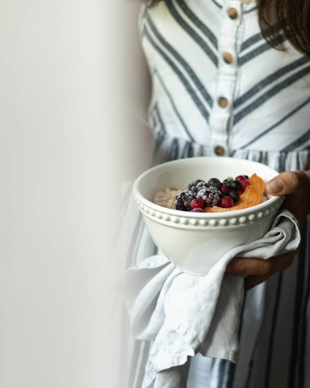 woman in white and gray stripe dress holding bowl of berries