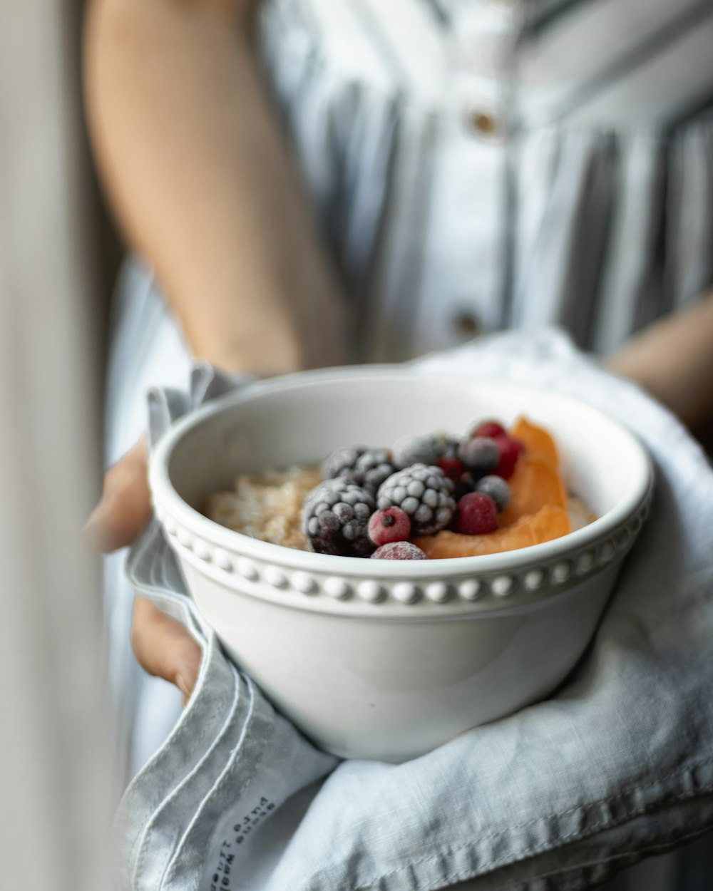 person holding white ceramic bowl with fruits
