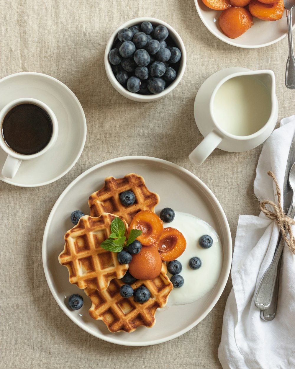 waffle with sliced strawberries and blueberries on white ceramic plate
