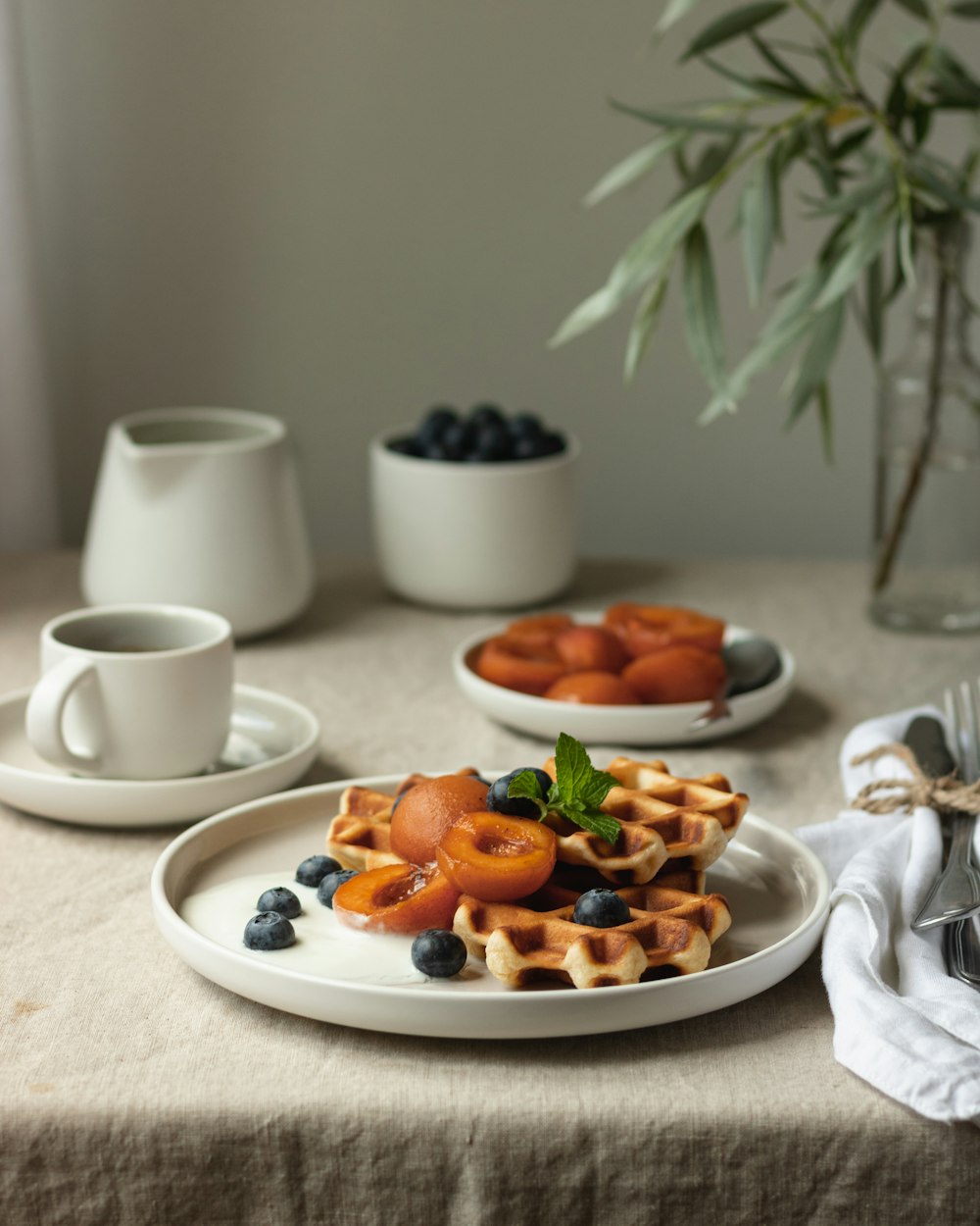 テーブルの上の白い陶器のマグカップの横の白い陶器の皿の上のスライスされたフルーツ