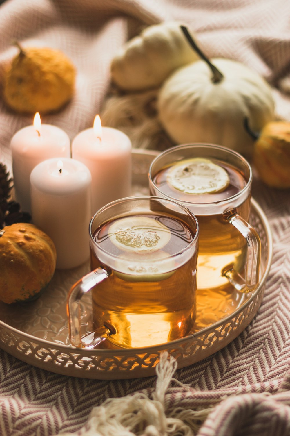 white pillar candle beside clear glass mug with brown liquid