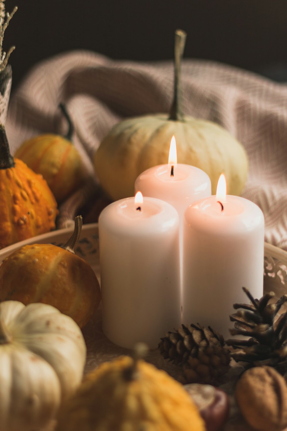 white pillar candle beside orange pumpkin and white pumpkin