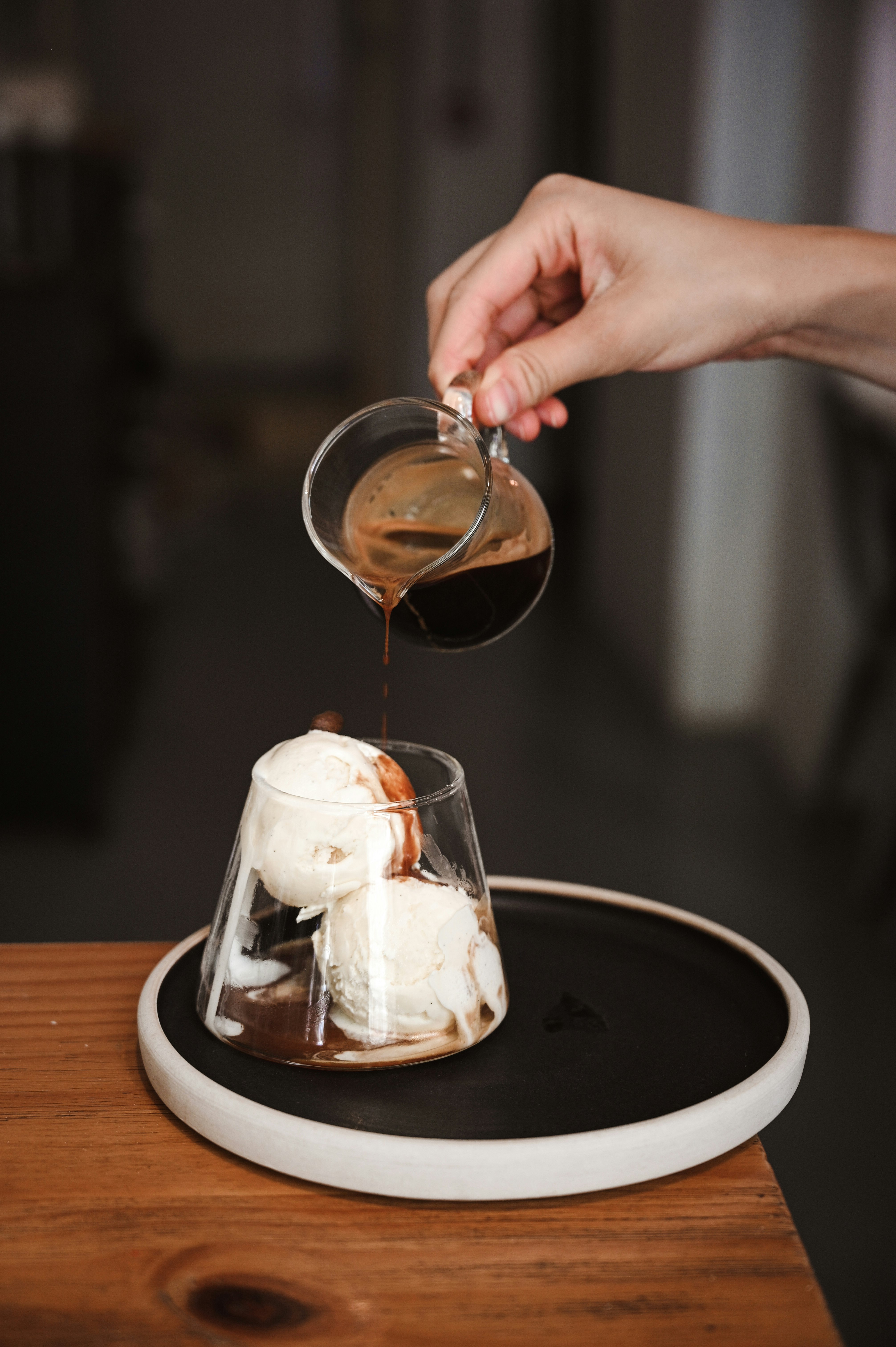 person pouring brown liquid on clear drinking glass