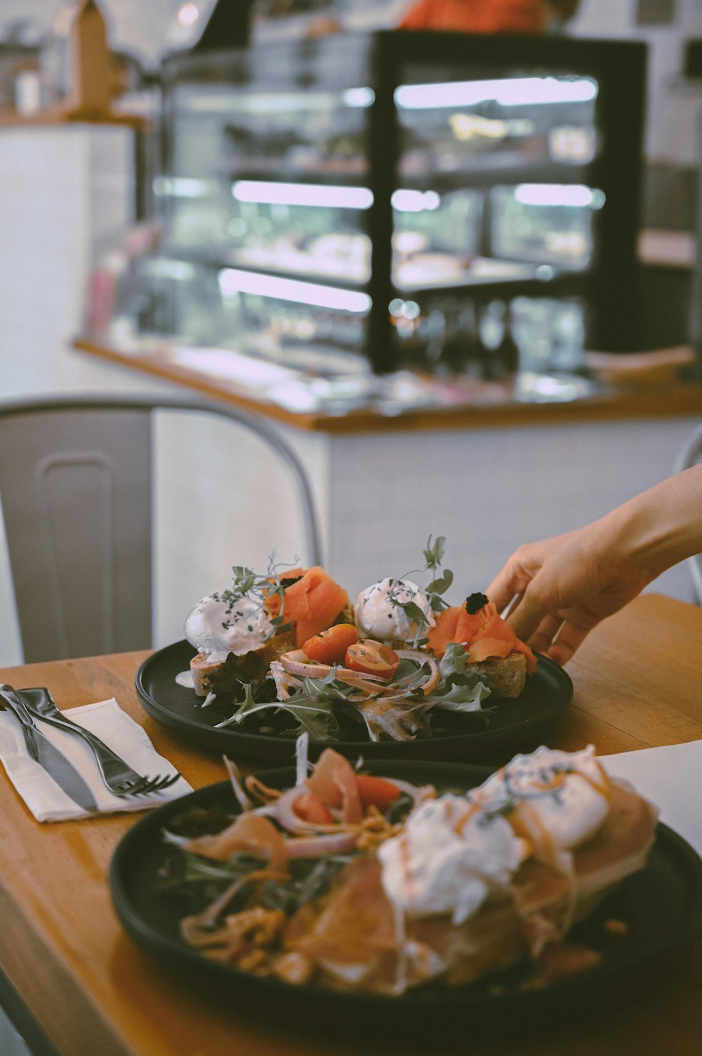 person holding a black ceramic bowl with vegetables