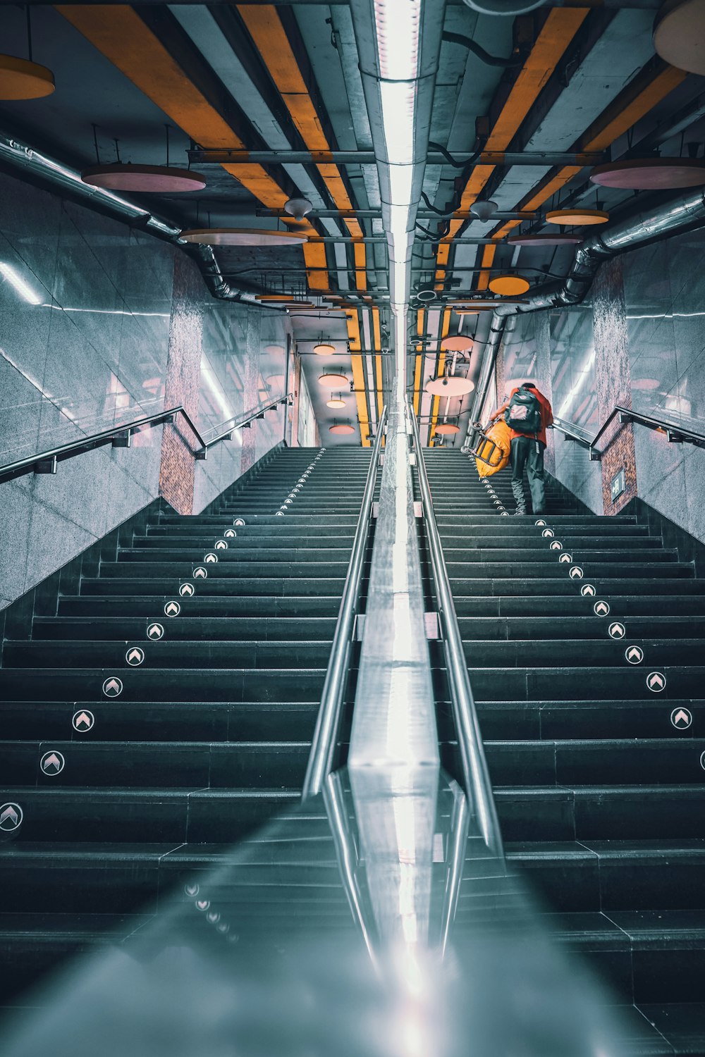 man in black jacket and black pants walking on black escalator