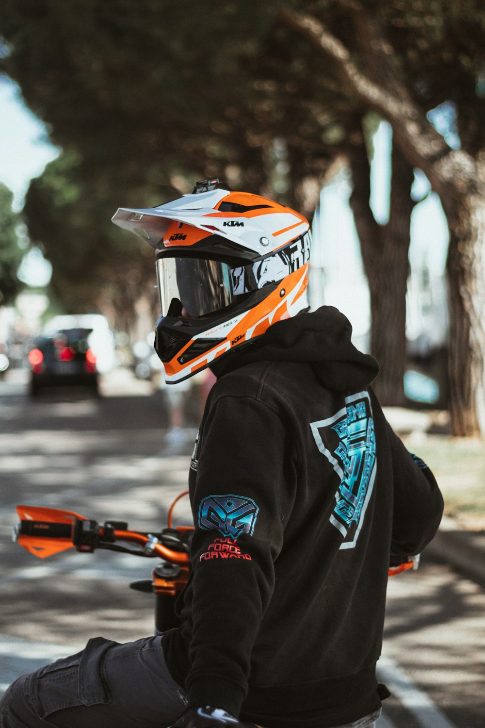 Persona con casco negro y naranja y sudadera con capucha negra sosteniendo una pistola nerf naranja y negra