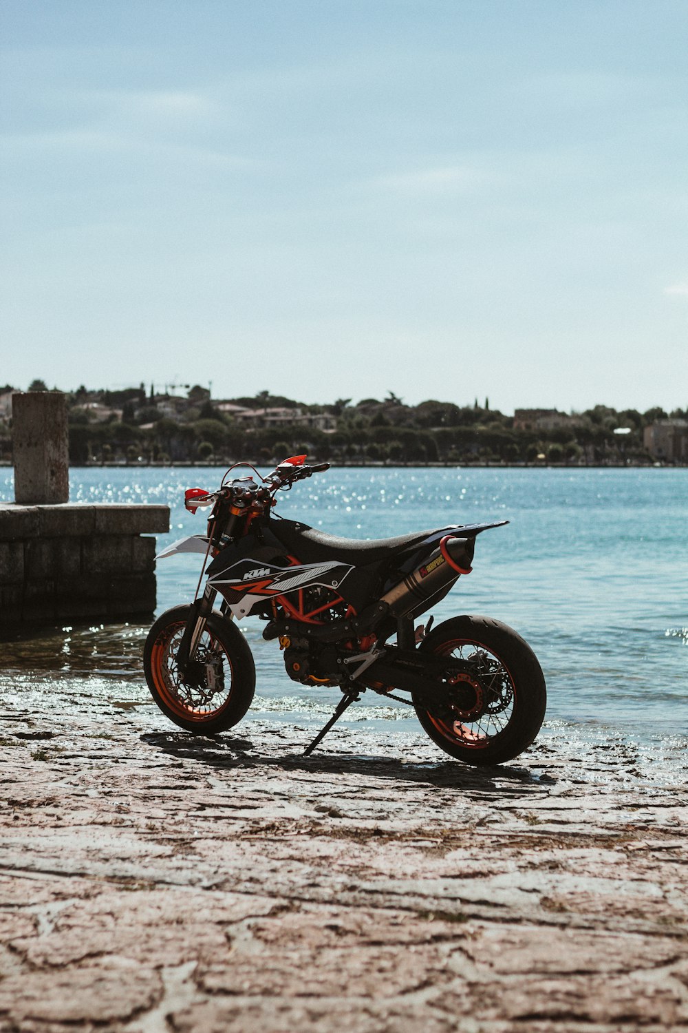 black motorcycle parked beside body of water during daytime