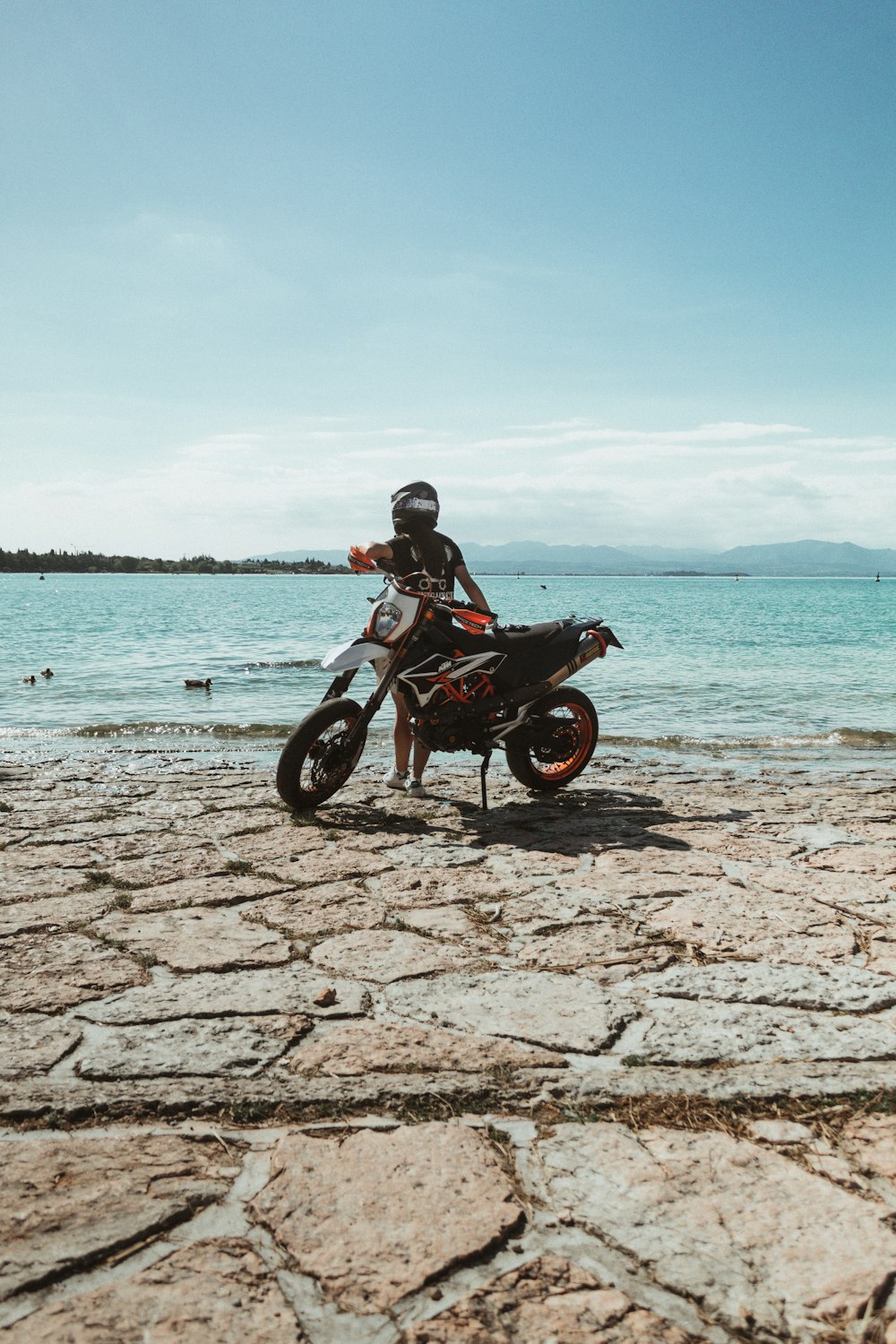 hombre con chaqueta negra montando motocicleta en la playa durante el día