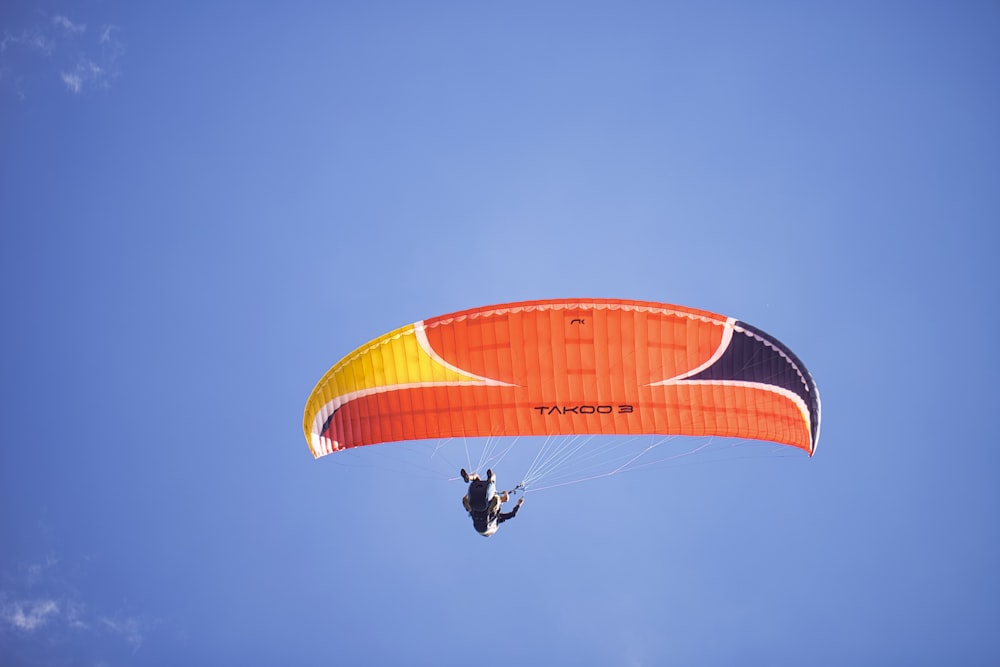 person in black jacket riding yellow and red parachute