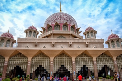 Exterior view of a mosque with people entering for prayer.